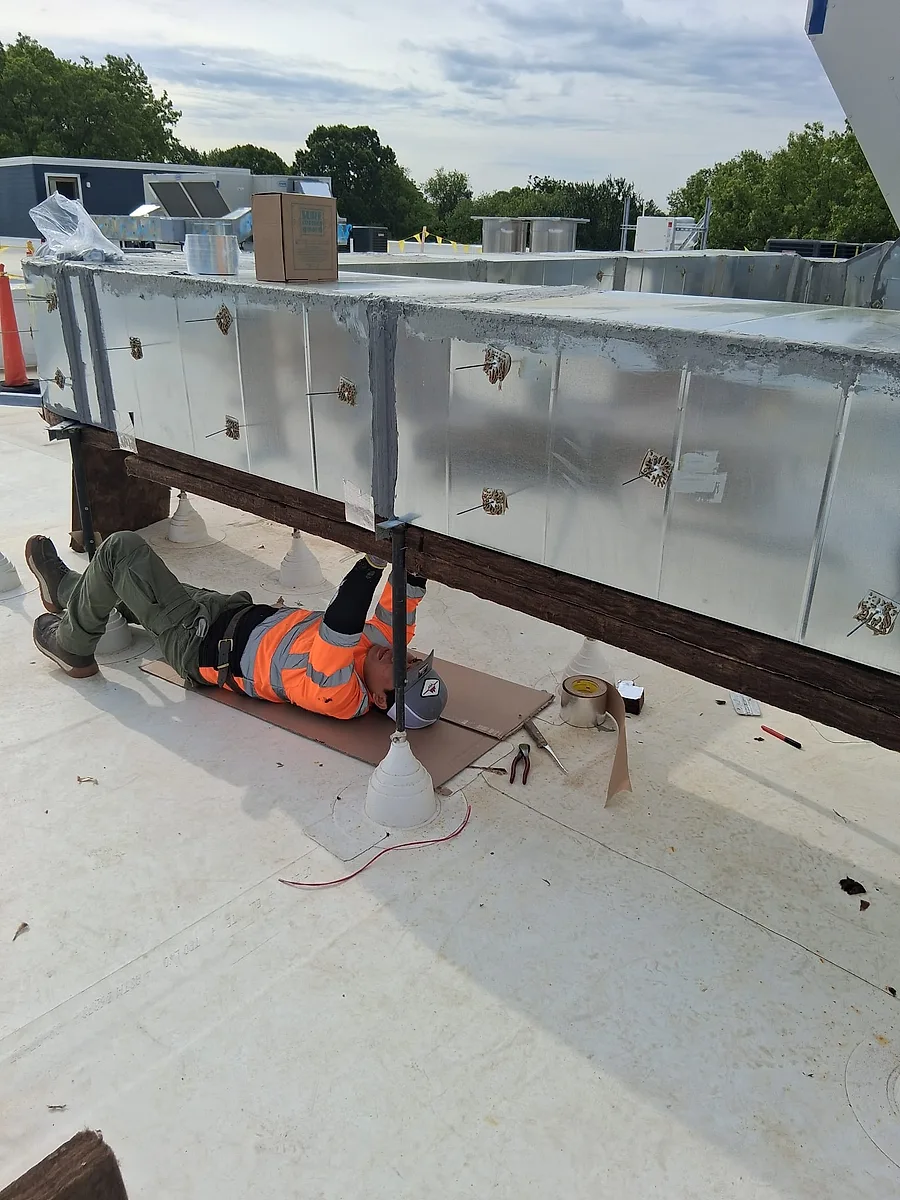 Instalador colocando envoltura de ducto en un tramo elevado de una obra comercial