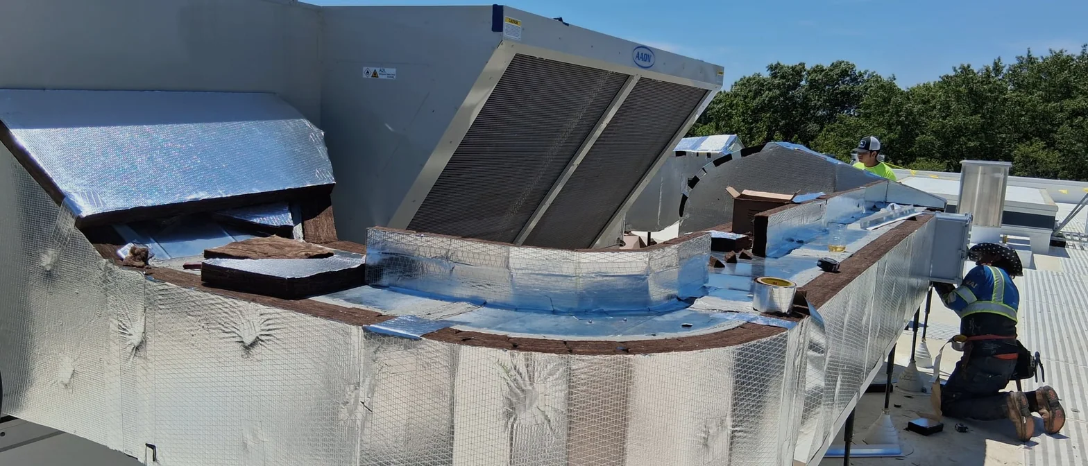 Aislador instalando forro de foil reflectivo sobre un plenum curvo de azotea