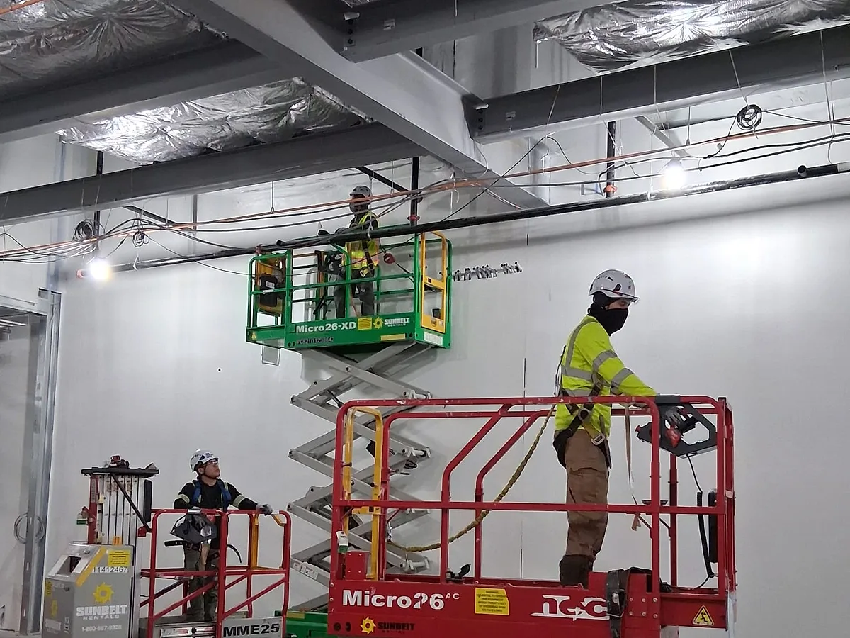 Equipo aislando la envolvente de un edificio comercial desde elevadores de tijera